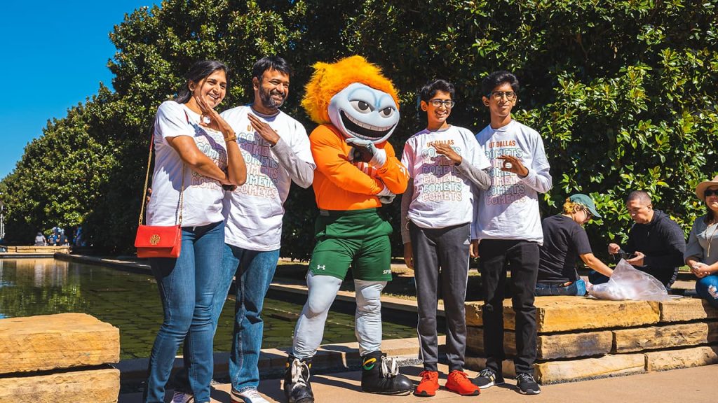 Temoc with UT Dallas family displaying the whoosh gesture.
